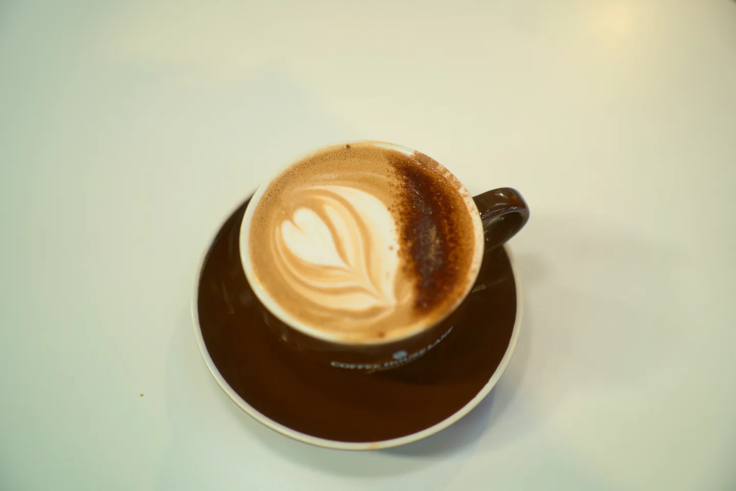 Cappuccino in a brown cup with leaf-shaped milk art