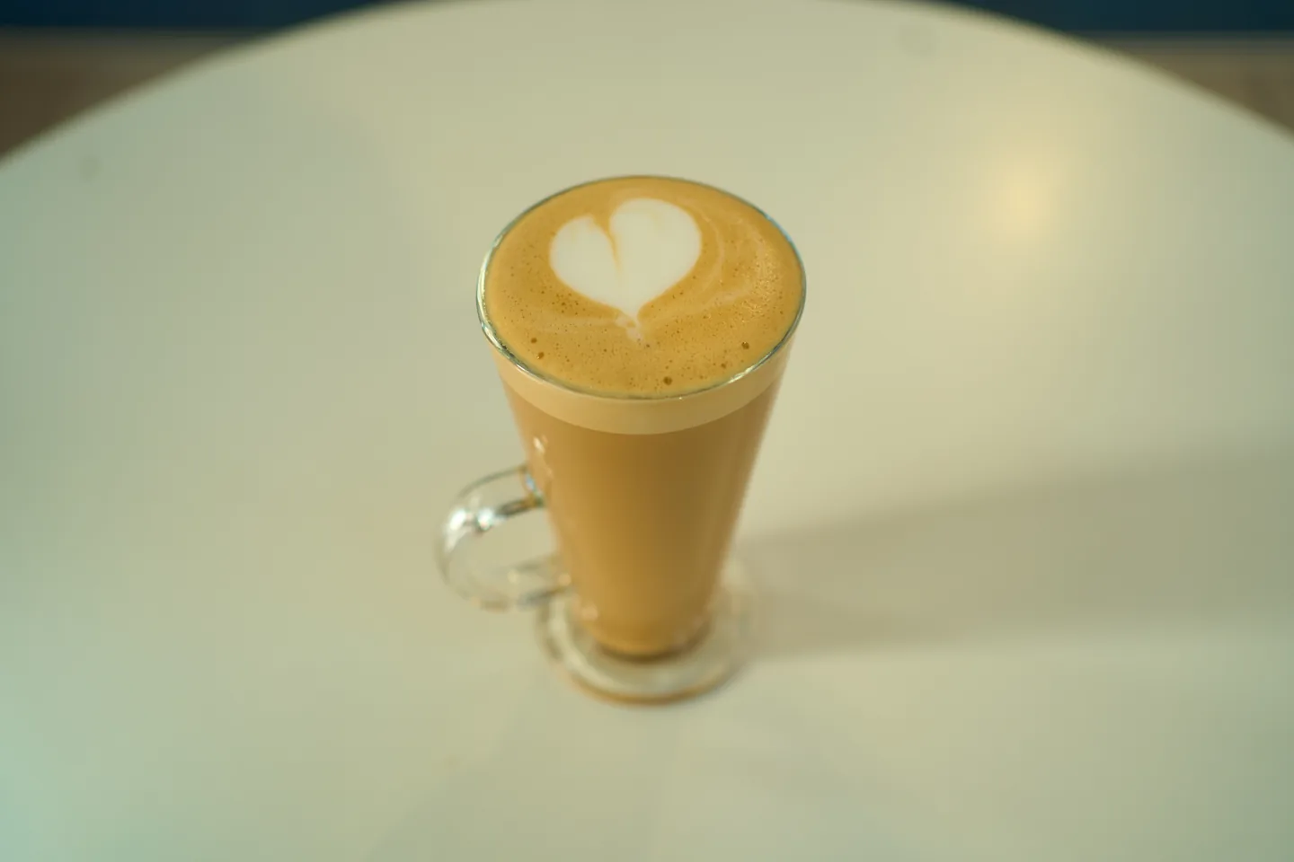 Latte in a clear glass with heart-shaped milk art