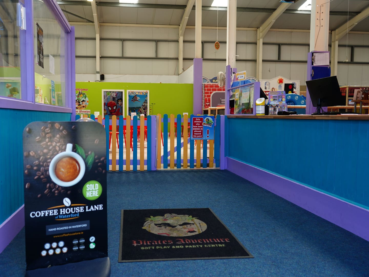 View through the blue entrance door towards the venue safety gate and reception.